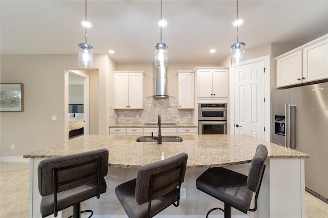 kitchen with stainless steel appliances, hanging light fixtures, and a center island with sink