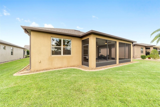 back of property with ceiling fan, a sunroom, and a yard