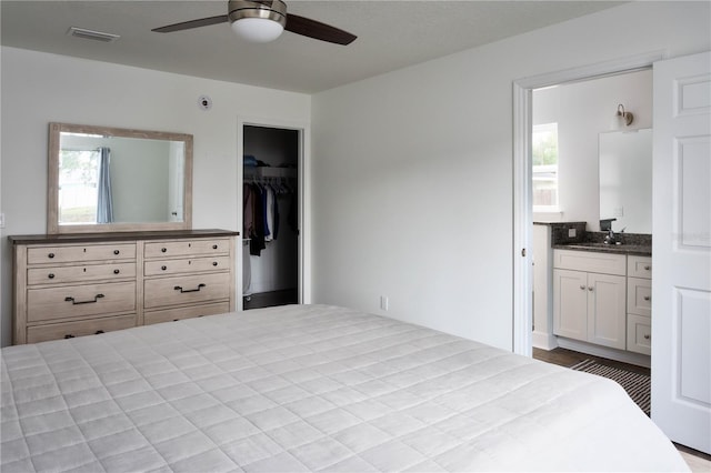 bedroom with multiple windows, ceiling fan, a closet, and ensuite bath