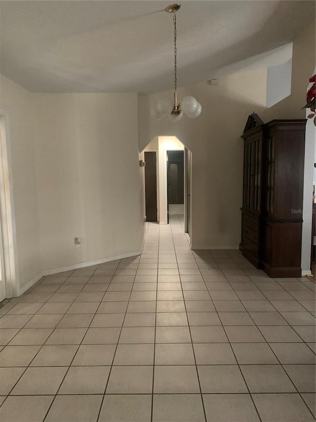 tiled spare room with a chandelier