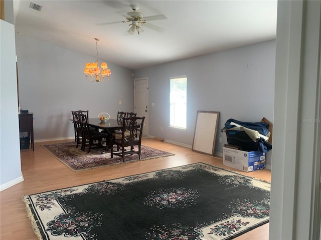 dining area featuring ceiling fan with notable chandelier, light hardwood / wood-style floors, and lofted ceiling