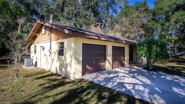 view of side of home featuring central AC unit, a garage, and a yard