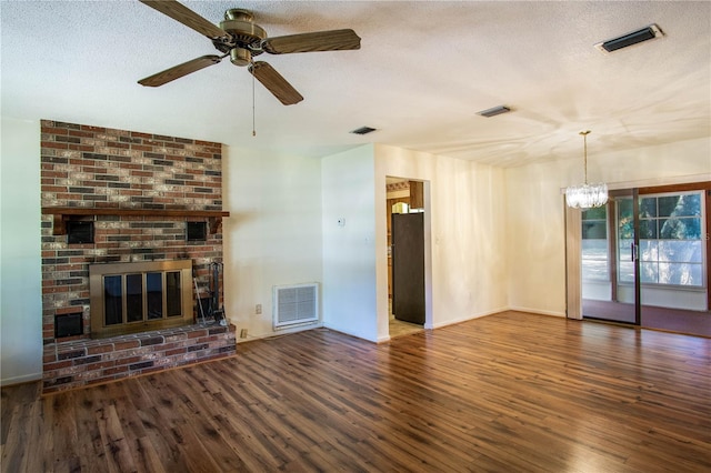 unfurnished living room featuring dark hardwood / wood-style floors, a fireplace, a textured ceiling, and ceiling fan with notable chandelier