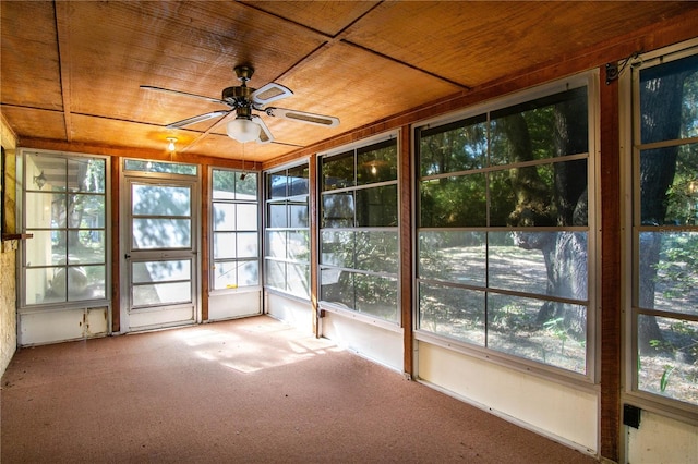 unfurnished sunroom featuring wood ceiling, ceiling fan, and a healthy amount of sunlight