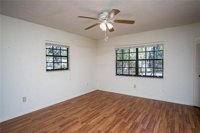 unfurnished room featuring ceiling fan, dark hardwood / wood-style flooring, a healthy amount of sunlight, and a textured ceiling