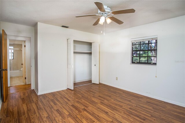 unfurnished bedroom with dark hardwood / wood-style floors, ceiling fan, a textured ceiling, and a closet