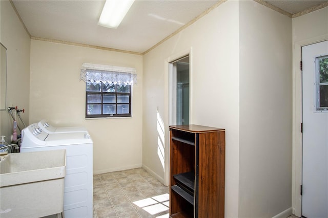 washroom with crown molding, a healthy amount of sunlight, washing machine and dryer, and sink