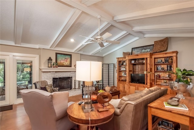 living room with light wood-type flooring, a brick fireplace, a textured ceiling, ceiling fan, and lofted ceiling with beams