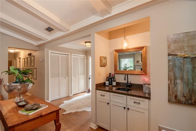 bar featuring white cabinetry, tile patterned flooring, hanging light fixtures, and a textured ceiling