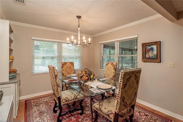 dining room with hardwood / wood-style flooring, a notable chandelier, ornamental molding, and a textured ceiling