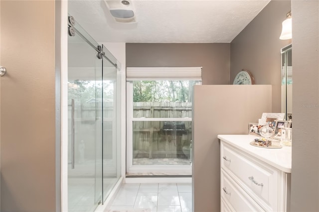 bathroom with tile patterned flooring, vanity, an enclosed shower, and a textured ceiling