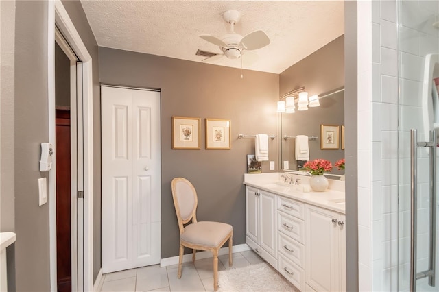 bathroom featuring ceiling fan, tile patterned flooring, a textured ceiling, vanity, and a shower with shower door