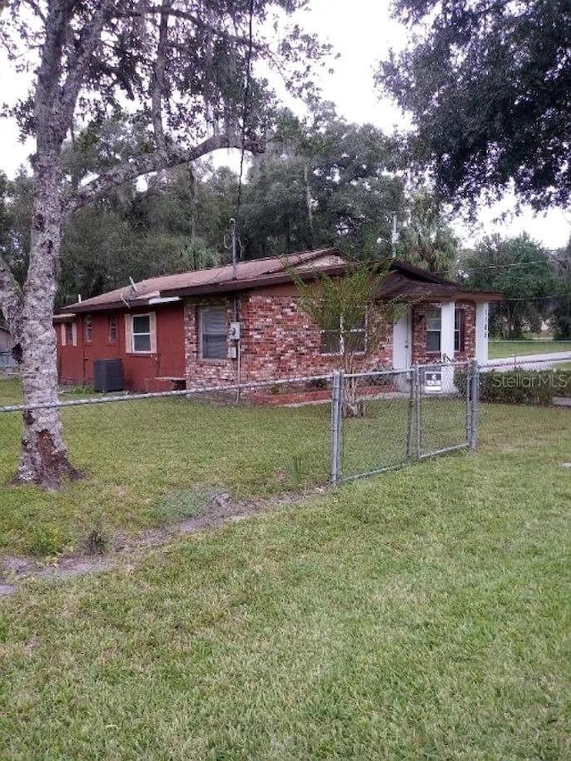 view of front of house featuring cooling unit and a front yard