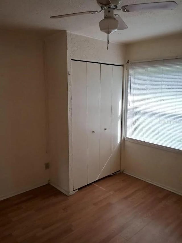 unfurnished bedroom featuring ceiling fan, light wood-type flooring, and a closet