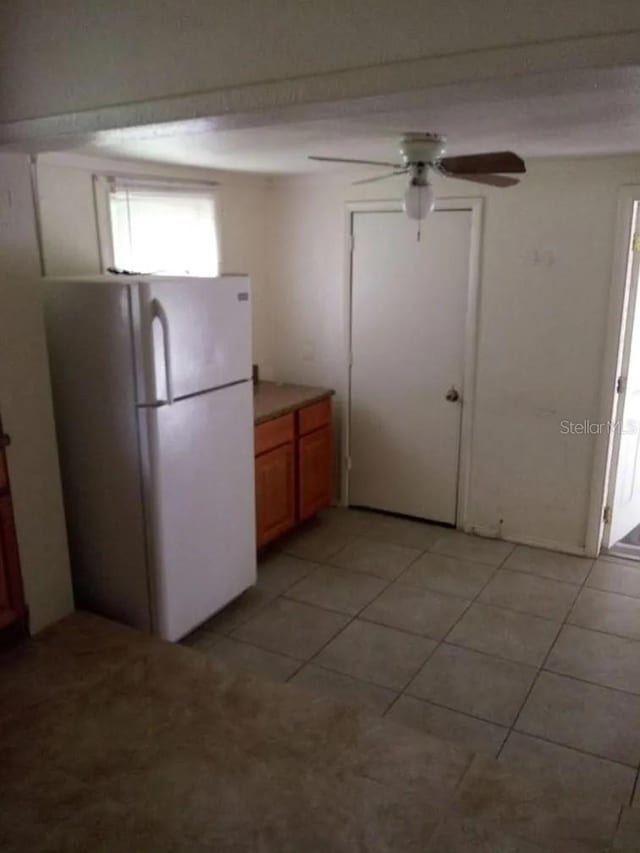 kitchen featuring ceiling fan, white refrigerator, and light tile patterned floors