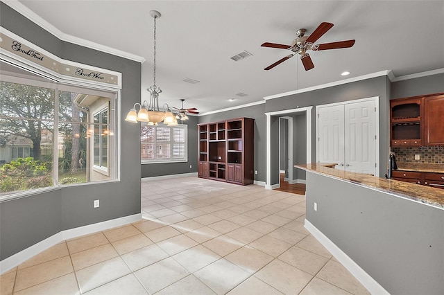 interior space featuring light tile patterned flooring, light stone counters, backsplash, decorative light fixtures, and crown molding