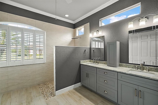 bathroom with wood-type flooring, tile walls, vanity, crown molding, and walk in shower