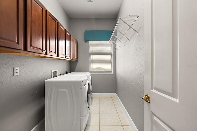 laundry area with washing machine and clothes dryer, light tile patterned flooring, and cabinets