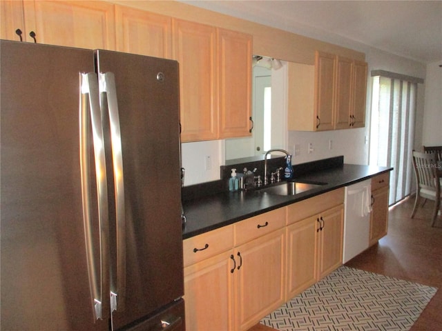 kitchen featuring light brown cabinetry, white dishwasher, stainless steel refrigerator, and sink