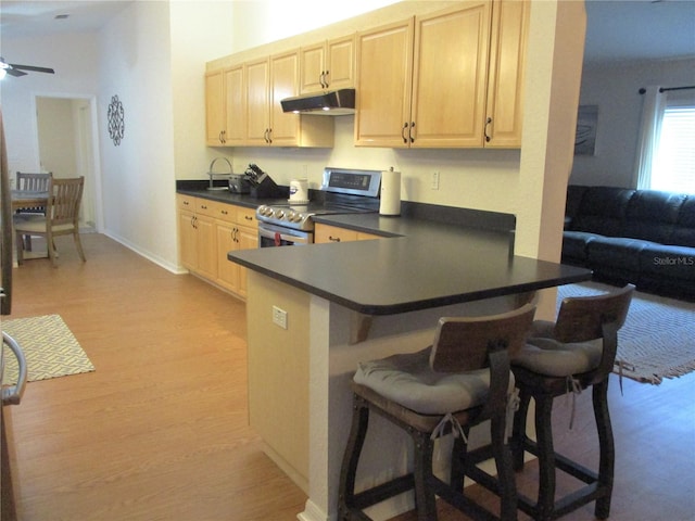 kitchen with ceiling fan, stainless steel electric range oven, light wood-type flooring, a kitchen bar, and kitchen peninsula