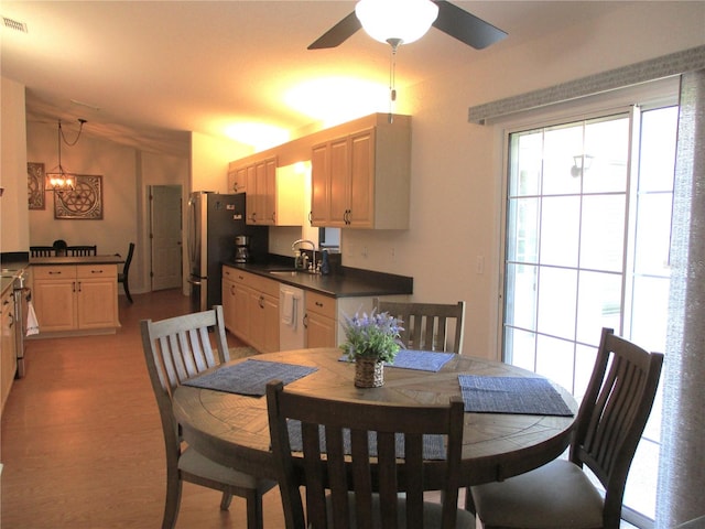 dining area with vaulted ceiling, sink, ceiling fan with notable chandelier, and light hardwood / wood-style flooring