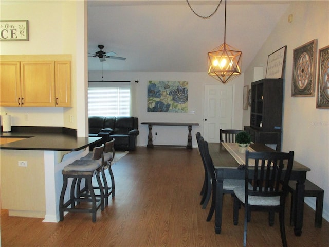 dining area featuring ceiling fan with notable chandelier, dark hardwood / wood-style flooring, and vaulted ceiling