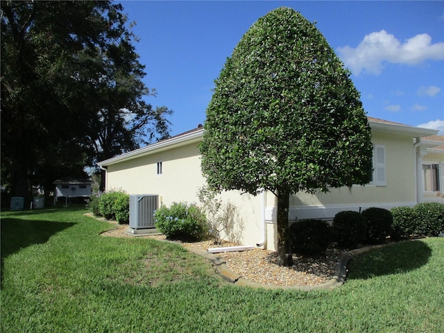 view of side of property with a yard and central AC