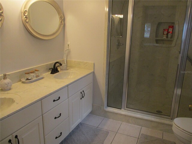 bathroom with toilet, vanity, tile patterned floors, and walk in shower