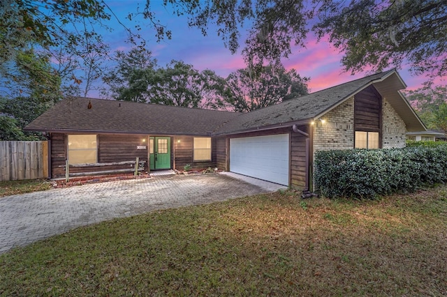 ranch-style home featuring a garage and a yard