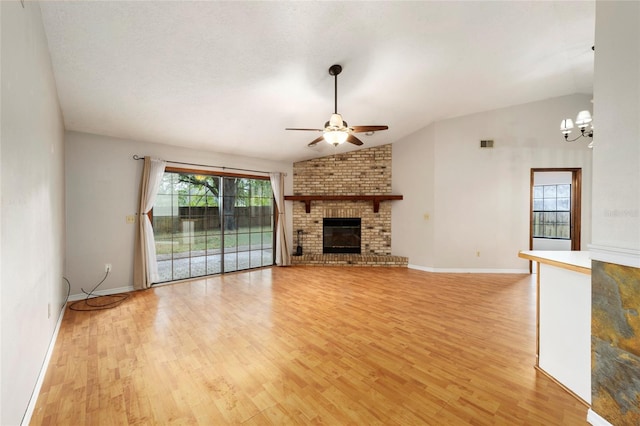 unfurnished living room featuring a fireplace, plenty of natural light, light hardwood / wood-style floors, and vaulted ceiling