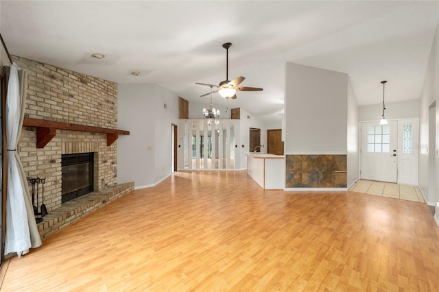 unfurnished living room featuring sink, ceiling fan, high vaulted ceiling, a brick fireplace, and light wood-type flooring