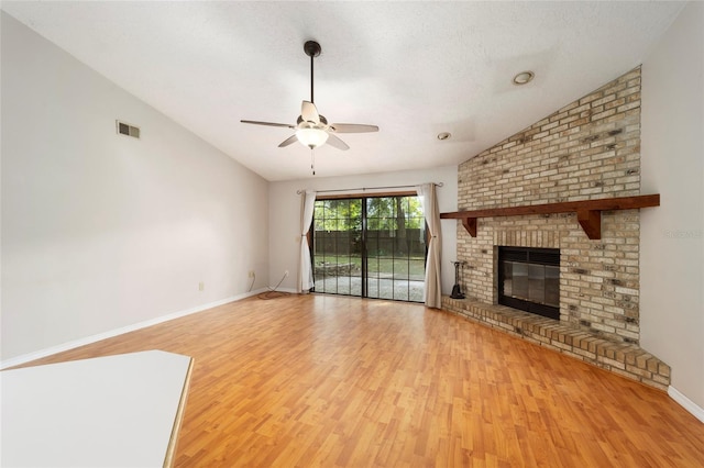 unfurnished living room featuring light wood-type flooring, lofted ceiling, ceiling fan, and a brick fireplace