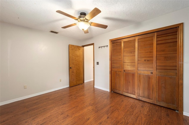 unfurnished bedroom featuring a textured ceiling, dark hardwood / wood-style flooring, ceiling fan, and a closet