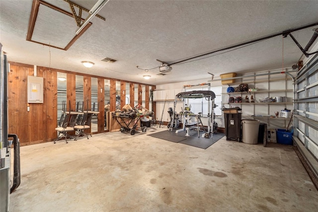 exercise room featuring concrete flooring, a textured ceiling, and wood walls