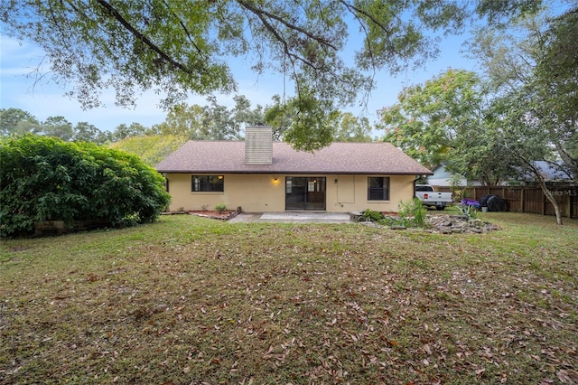 rear view of property featuring a lawn and a patio area