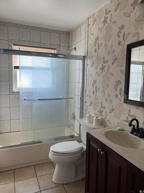 full bathroom with toilet, vanity, bath / shower combo with glass door, and tile patterned floors