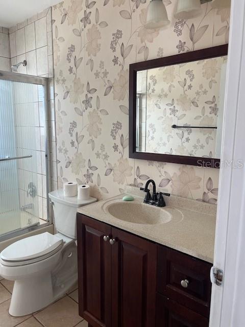 full bathroom with combined bath / shower with glass door, tile patterned floors, toilet, and vanity