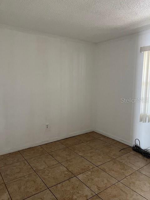 spare room with a textured ceiling and light tile patterned flooring