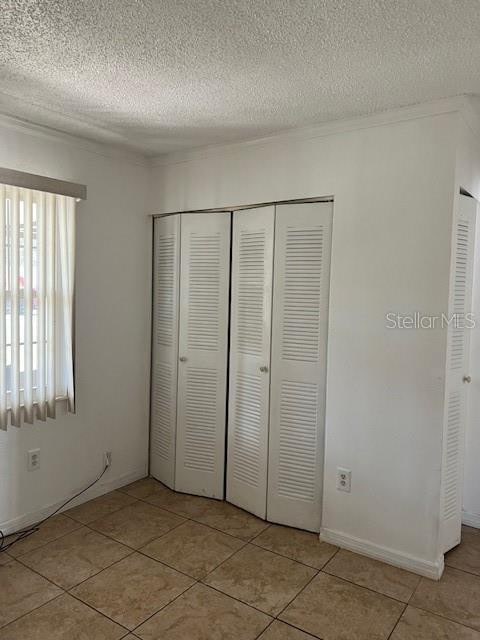 unfurnished bedroom with light tile patterned floors, a textured ceiling, and a closet