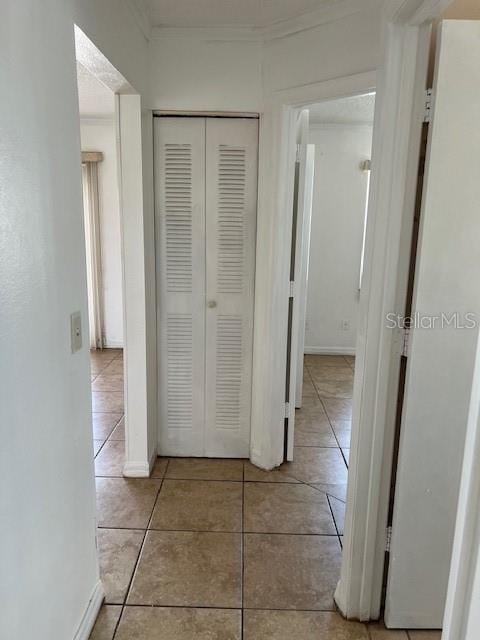 hallway featuring light tile patterned floors and crown molding