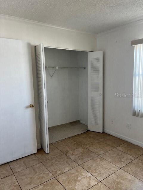 unfurnished bedroom featuring light tile patterned flooring, a textured ceiling, and a closet