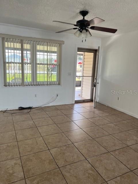 empty room with light tile patterned flooring, ceiling fan, and a textured ceiling