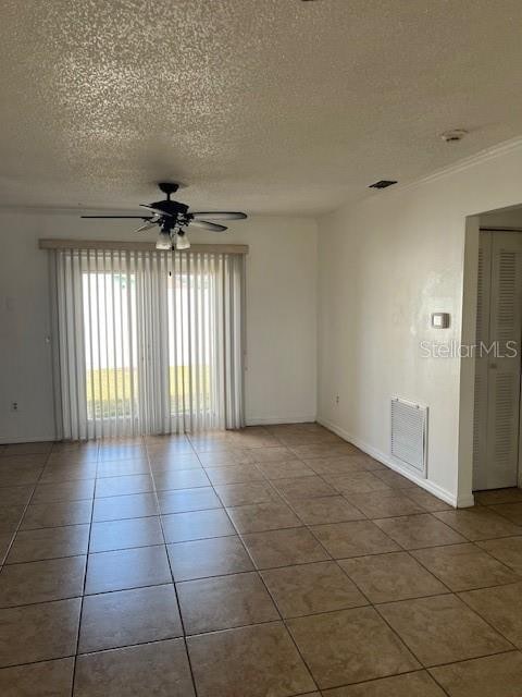 tiled spare room featuring ceiling fan, a textured ceiling, and ornamental molding