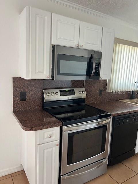 kitchen with appliances with stainless steel finishes, a textured ceiling, light tile patterned floors, backsplash, and white cabinets