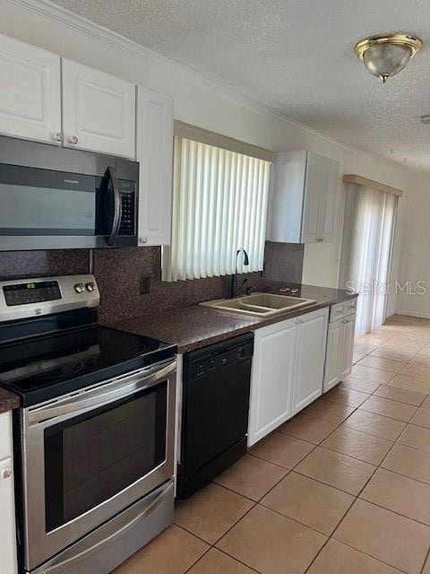 kitchen featuring sink, appliances with stainless steel finishes, tasteful backsplash, light tile patterned floors, and white cabinets