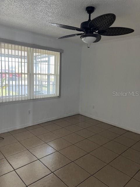 empty room featuring a textured ceiling, tile patterned flooring, and ceiling fan