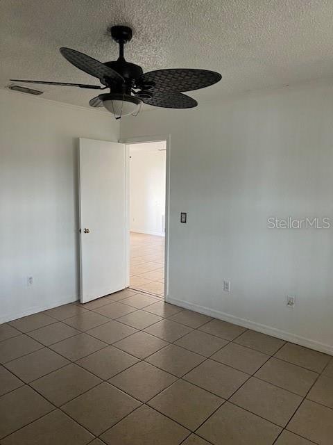 empty room with ceiling fan, a textured ceiling, and tile patterned flooring