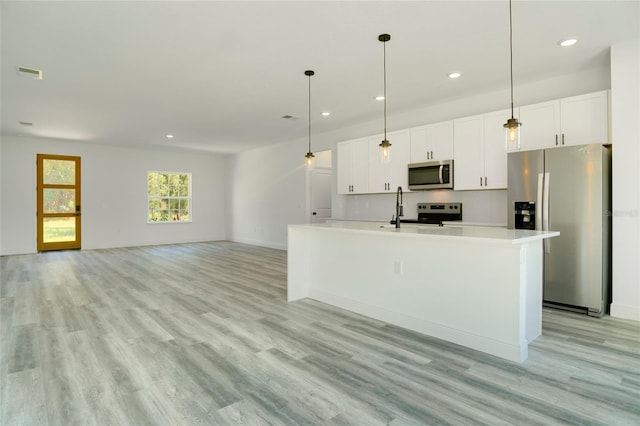 kitchen with light hardwood / wood-style flooring, white cabinets, appliances with stainless steel finishes, and a kitchen island with sink