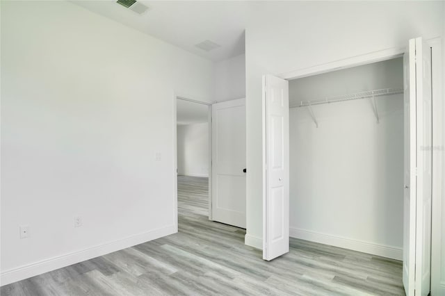 unfurnished bedroom with a closet and light hardwood / wood-style floors