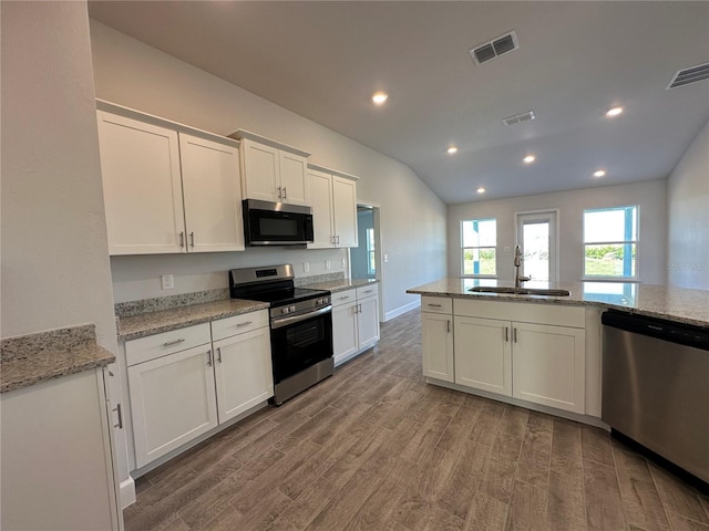 4489 SW 90th Pl, Ocala, FL 34476 - kitchen with appliances with stainless steel finishes, a sink, light wood-style floors, white cabinets, and light stone counters